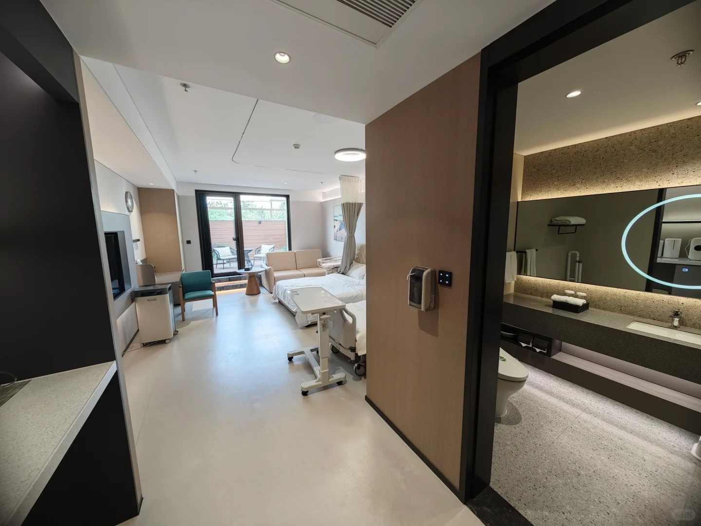 Private inpatient room with bed, bathroom, and balcony